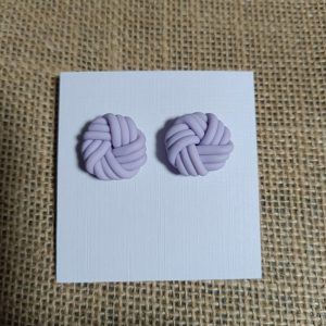 Lavender polymer clay earrings shaped like knots on a white card.