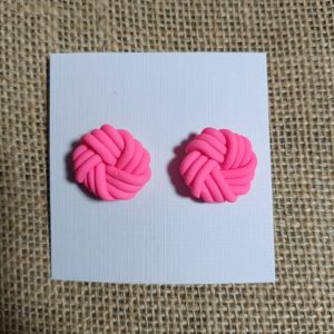 Pink polymer clay earrings shaped like knots on a white card.