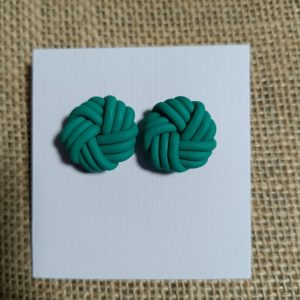 Teal polymer clay earrings shaped like knots on a white display card.
