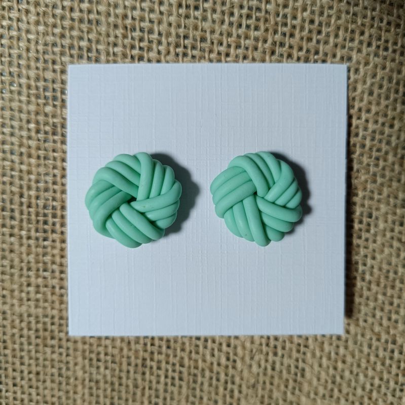 Mint green polymer clay knot earrings on a white card.