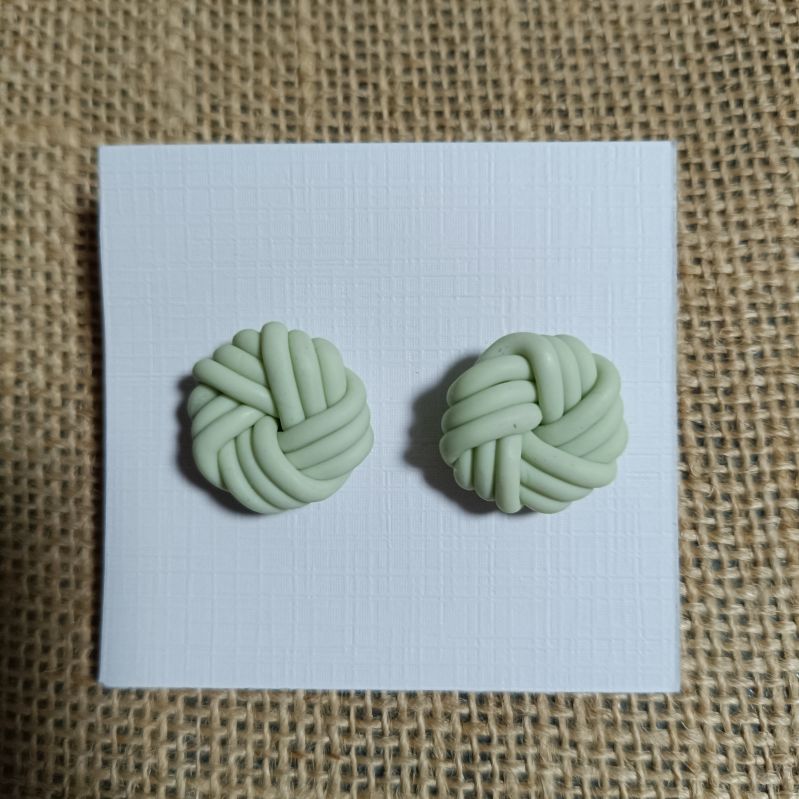 Handmade polymer clay earrings in a knot design, light green color.