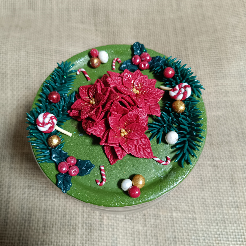Decorated mug featuring red flowers and festive elements on a green surface.