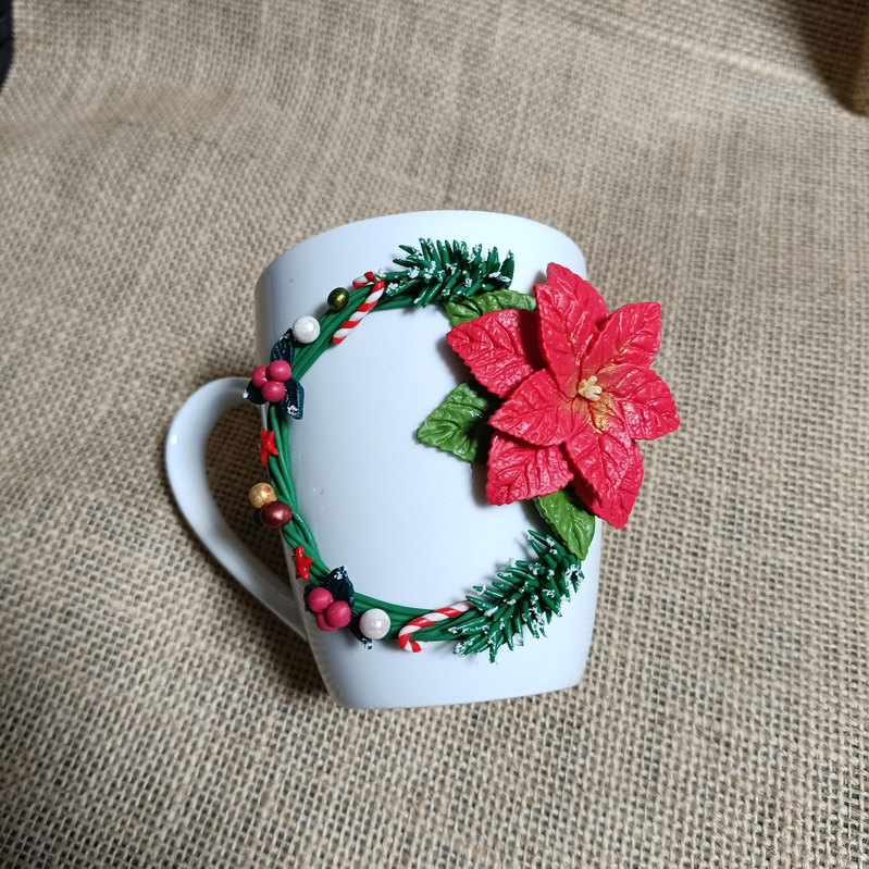 White mug decorated with a red flower and green foliage.