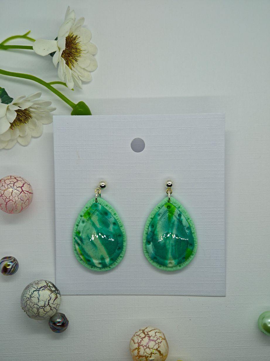 Teardrop earrings in green with silver-tone hooks displayed on a card.