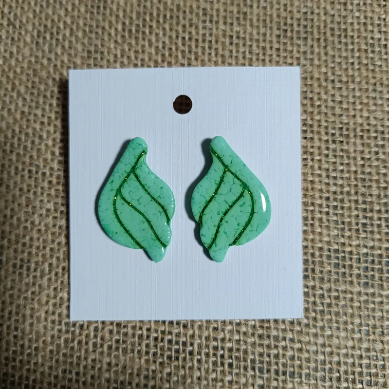 Green leaf-shaped earrings with a glossy finish on a white card.