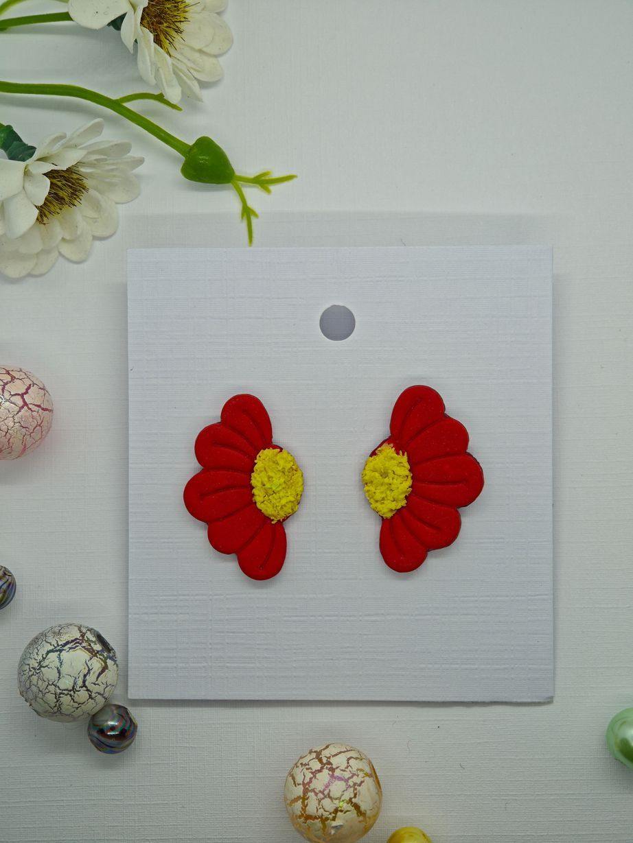 Red flower-shaped earrings with yellow centers on a display card.
