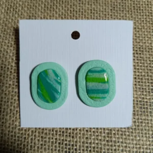 Handmade earrings featuring marbled green and blue cabochon design on a mint background.