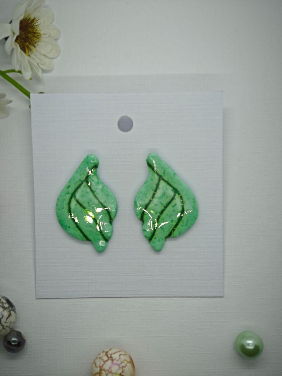 Green leaf-shaped earrings with a glossy finish on a display card.