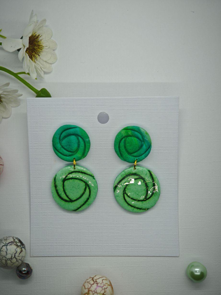Green polymer clay earrings with spiral design on a display card.